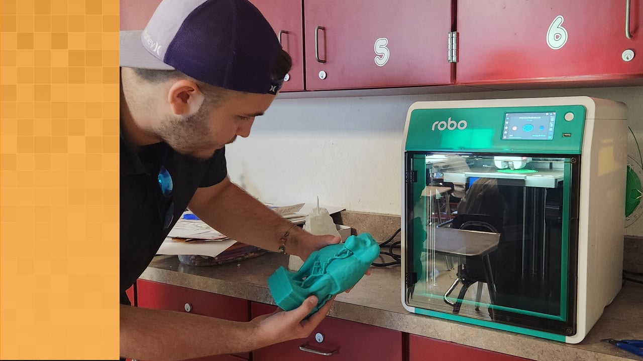 A teacher holds a 3D-printed replica of an ancient monkey god after having it printed using the Robo E4 3D printer.