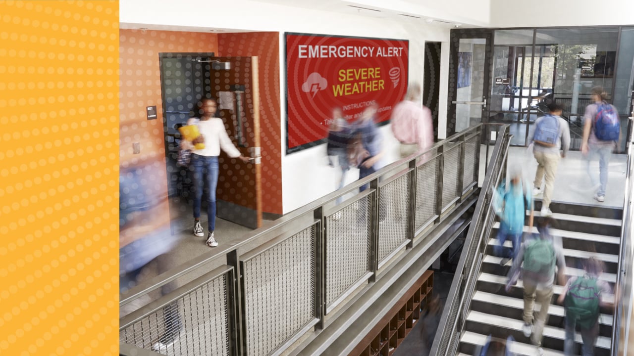 Busy hallway with Boxlight digital signage featuring an emergency alert message on screen via Attention campus communication solution.
