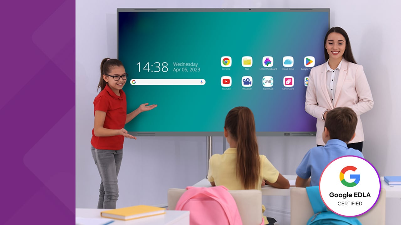 Smiling teacher standing to the right of a MimioPro G Google EDLA certified interactive display. Standing to the left of the MimioPro G is a student showing the class the homescreen.
